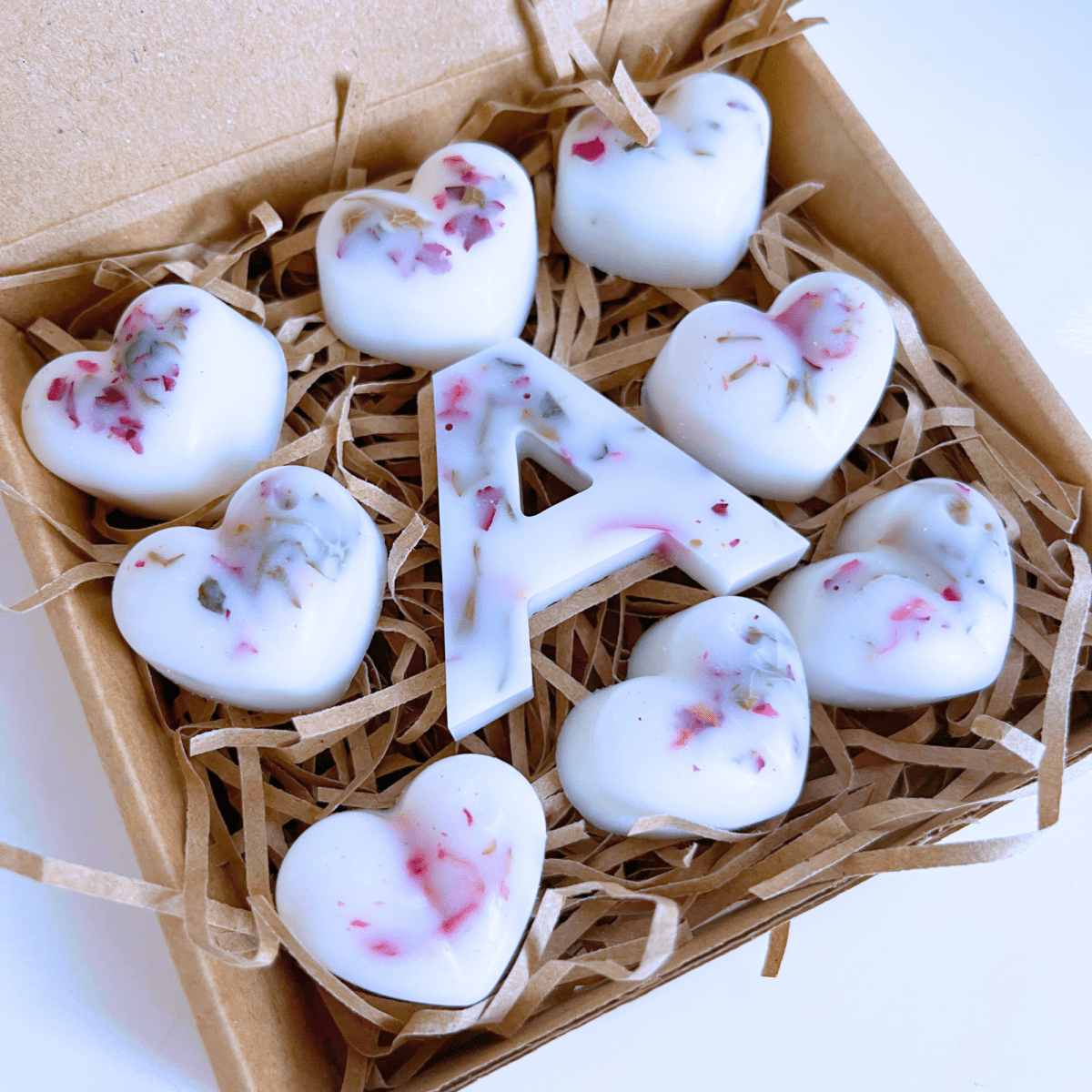 Close-up personalised love heart wax melts with rose petals and Rhubarb Rose & Musk fragrance.